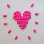 Pink pills arranged in a heart shape on a neutral surface. Perfect for health and medication themes.