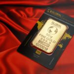 A 50g fine gold bar displayed elegantly on a rich red fabric background, symbolizing wealth and luxury.