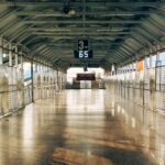 A deserted railway platform with a large digital clock, casting reflective patterns on the floor in Khordha, India.