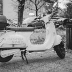 Electric scooter parked on a city sidewalk, available for rental, in a black and white urban scene.