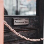 Close-up of an 'Employees Only' sign on a rustic wooden door secured by a chain.