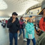 A bustling scene inside a modern train station with travelers and distinctive architectural design.