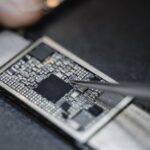 Detailed view of a technician using tweezers to fix an electronic circuit board.