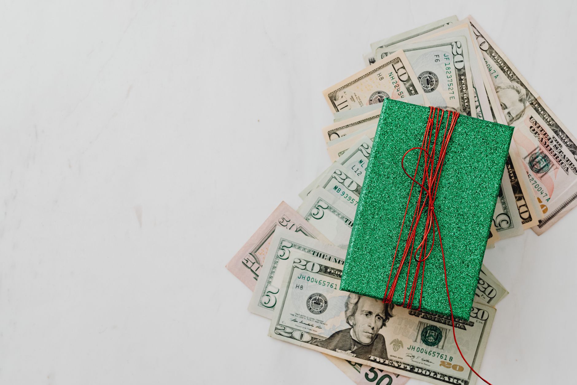 Green gift box on a pile of dollar banknotes showcasing a concept of monetary value and gift-giving.