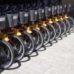 A neat row of bright yellow shared bicycles parked in an urban area, ready for public use.
