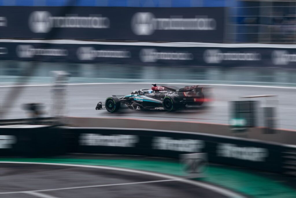 Dynamic shot of a racing car speeding during a Formula 1 event on a wet track.