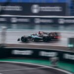 Dynamic shot of a racing car speeding during a Formula 1 event on a wet track.