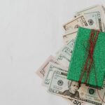 Green gift box on a pile of dollar banknotes showcasing a concept of monetary value and gift-giving.
