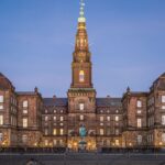 Stunning evening view of Christiansborg Palace with its illuminated spire in Copenhagen, Denmark.