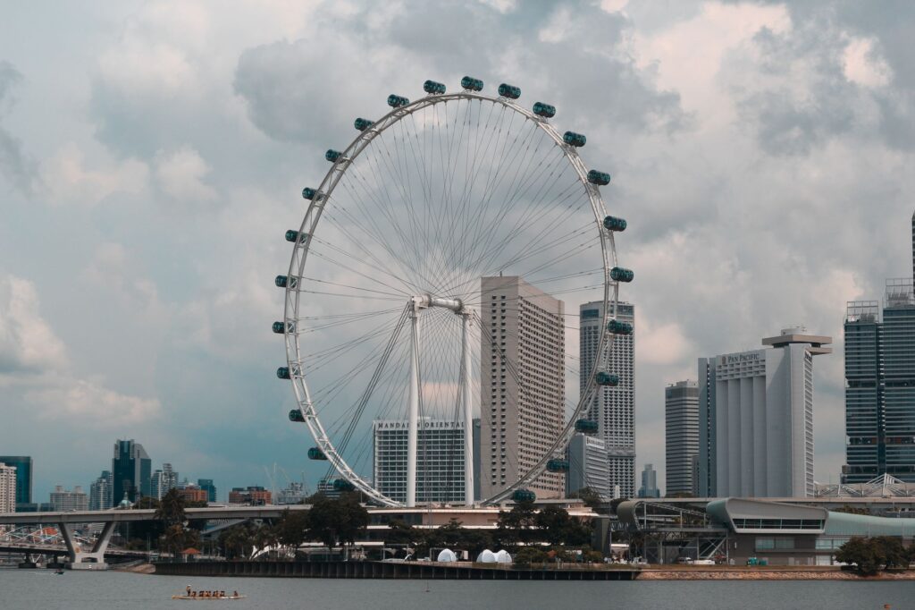 The iconic Singapore Flyer with city skyline on a cloudy day, showcasing urban architecture.
