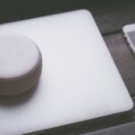 A smart speaker, laptop, and smartphone array representing modern technology lifestyle on a wooden surface.