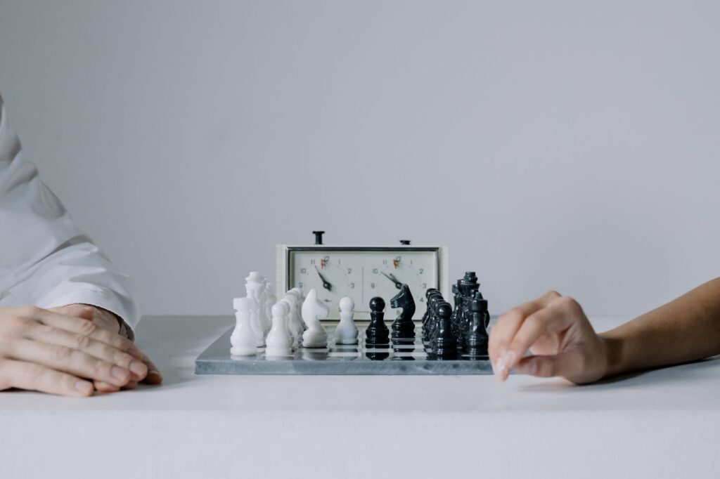 Two players engaged in a focused chess match with chess clock on table.