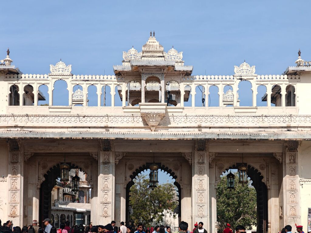 Crowds gather under the ornate gateway of Udaipur City Palace, a historic architectural gem.