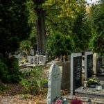 Peaceful cemetery with headstones surrounded by green trees and flowers.