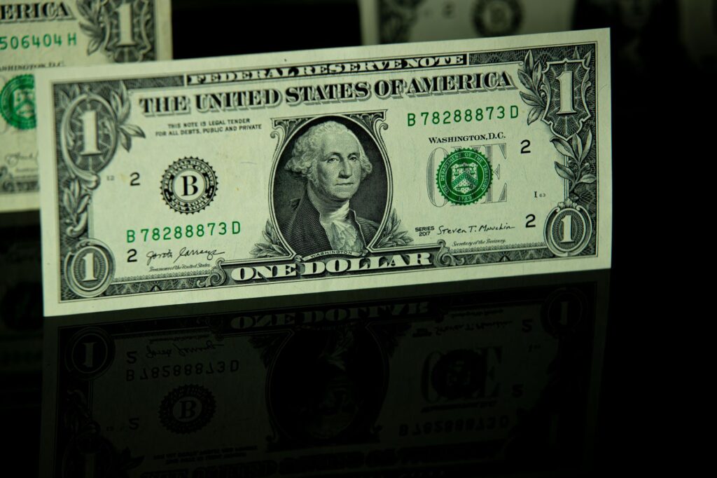 Detailed close-up of a US one-dollar bill with reflection, highlighting currency design.
