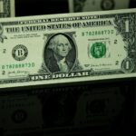 Detailed close-up of a US one-dollar bill with reflection, highlighting currency design.
