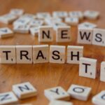 Close-up of wooden letter tiles spelling out Trash TV News on a table.