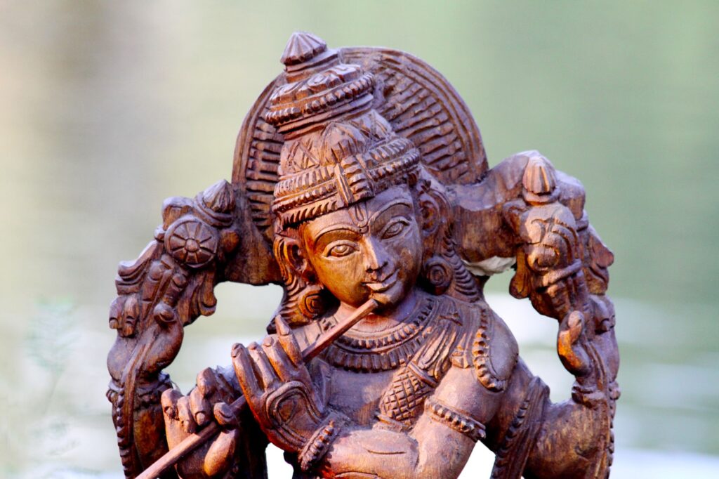 Close-up of a detailed wooden carving depicting a Hindu deity, highlighting artistic craftsmanship.