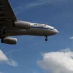 Air China airplane flying under a blue sky with clouds, in Frankfurt.