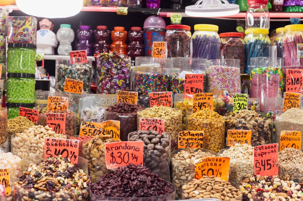 Vibrant display of candies and nuts in a Mexican market with colorful pricing tags.