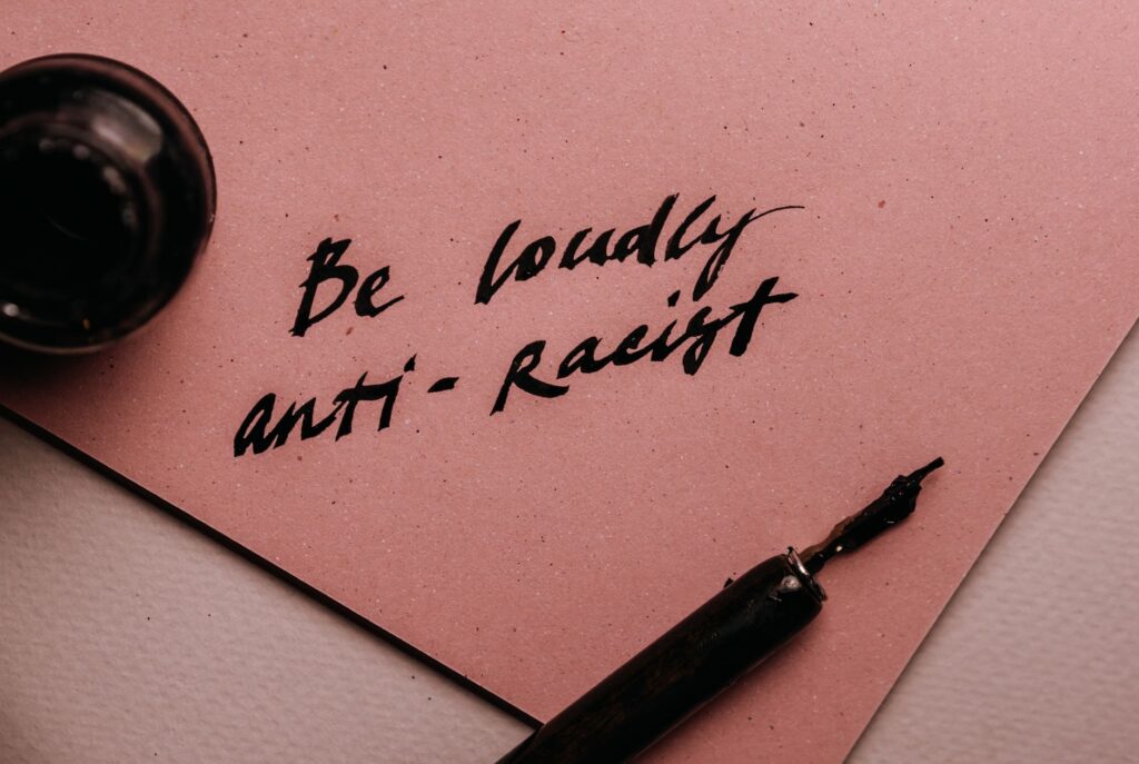 A powerful message on a pink surface promoting anti-racism with elegant calligraphy.