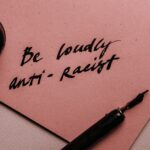 A powerful message on a pink surface promoting anti-racism with elegant calligraphy.
