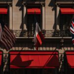 A classic building facade featuring US, French, and UK flags with vibrant red awnings.