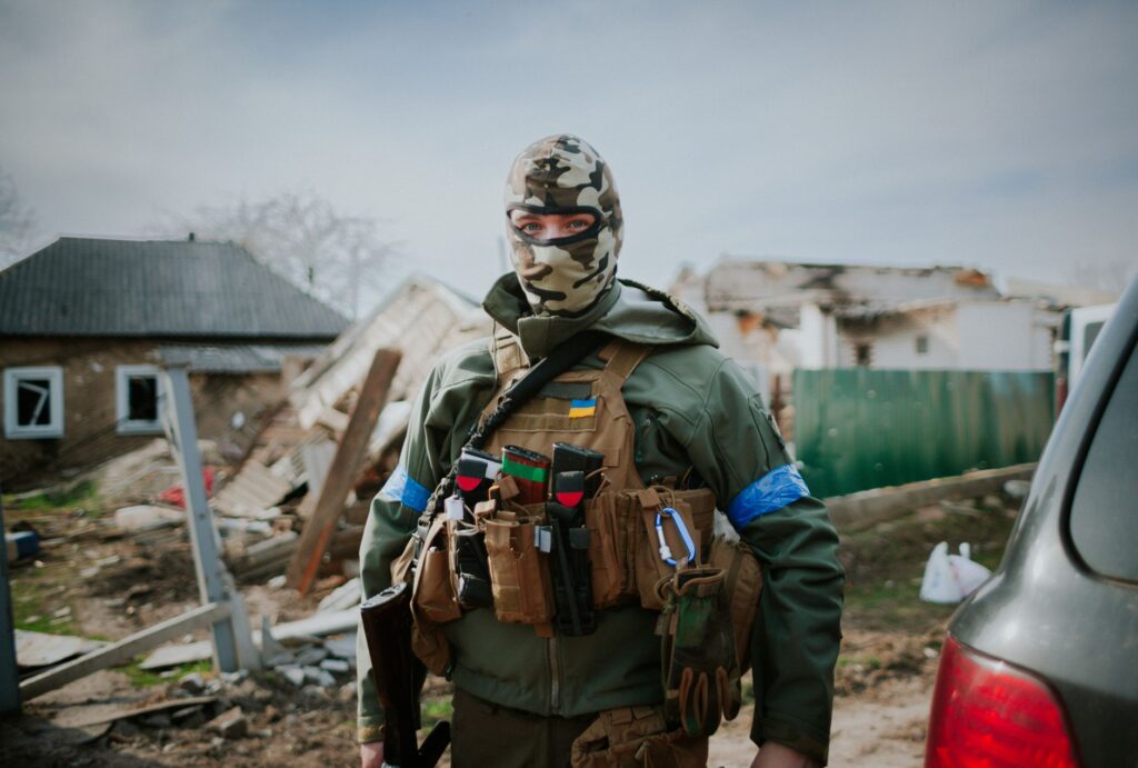 Soldier in camouflage gear standing in Kyiv Oblast, Ukraine amidst destruction.