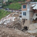 A residential building partially collapsed due to a natural disaster, showcasing severe structural damage.