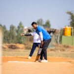 Two men playing cricket outdoors on a sunny day, focusing on the batsman preparing to hit.