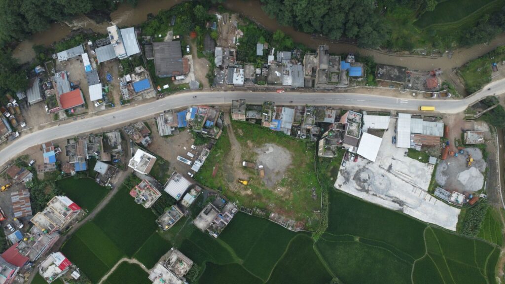 Explore the aerial view of Panauti, Nepal, showcasing green fields, roads, and village homes.