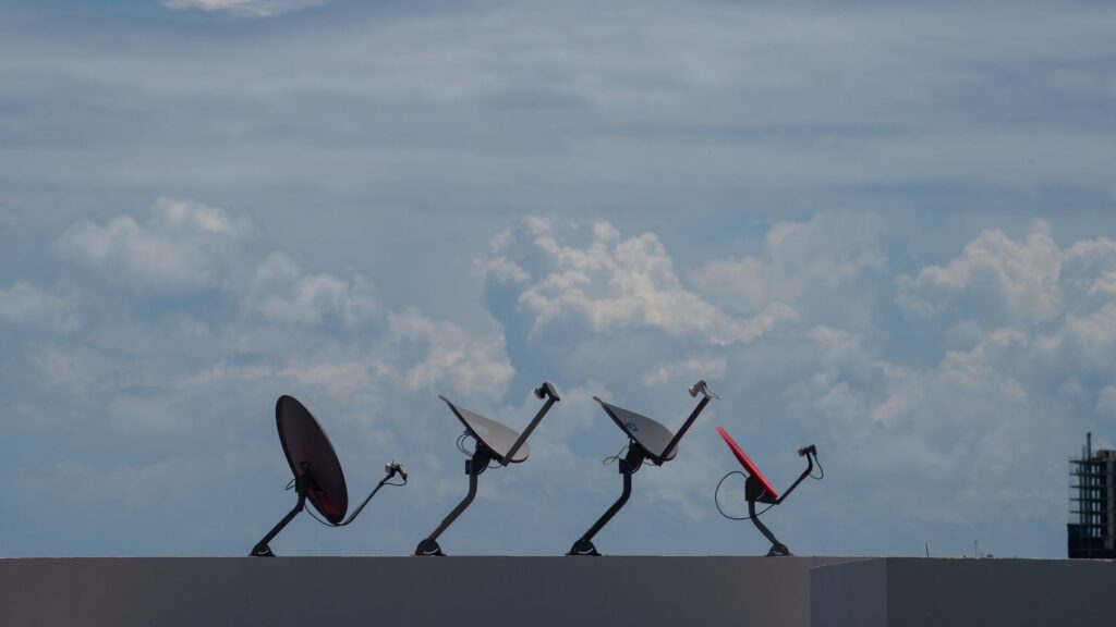 Four satellite dishes on a rooftop against a cloudy sky in Cancún, Mexico.