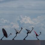 Four satellite dishes on a rooftop against a cloudy sky in Cancún, Mexico.