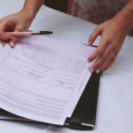 A detailed view of hands working with documents and a pen on a desk, ideal for business themes.