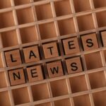 Wooden letter blocks spelling 'Latest News' on a grid surface. Ideal for media concepts.