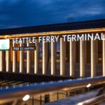 View of Seattle Ferry Terminal at night, showcasing illuminated signage and modern architecture.