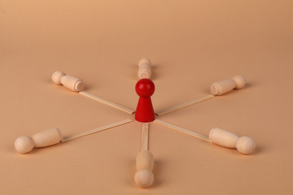Red leader figure connected to wooden figures, emphasizing leadership and teamwork.