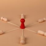 Red leader figure connected to wooden figures, emphasizing leadership and teamwork.
