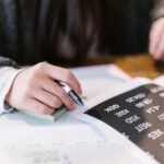 Close-up of a woman reviewing financial documents with focus on numbers and calculations.