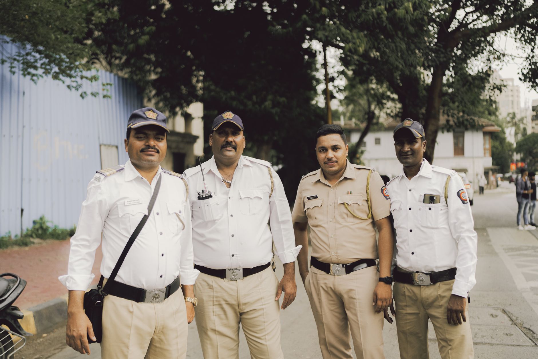 Four policemen in uniform standing on a street in Mumbai, India.