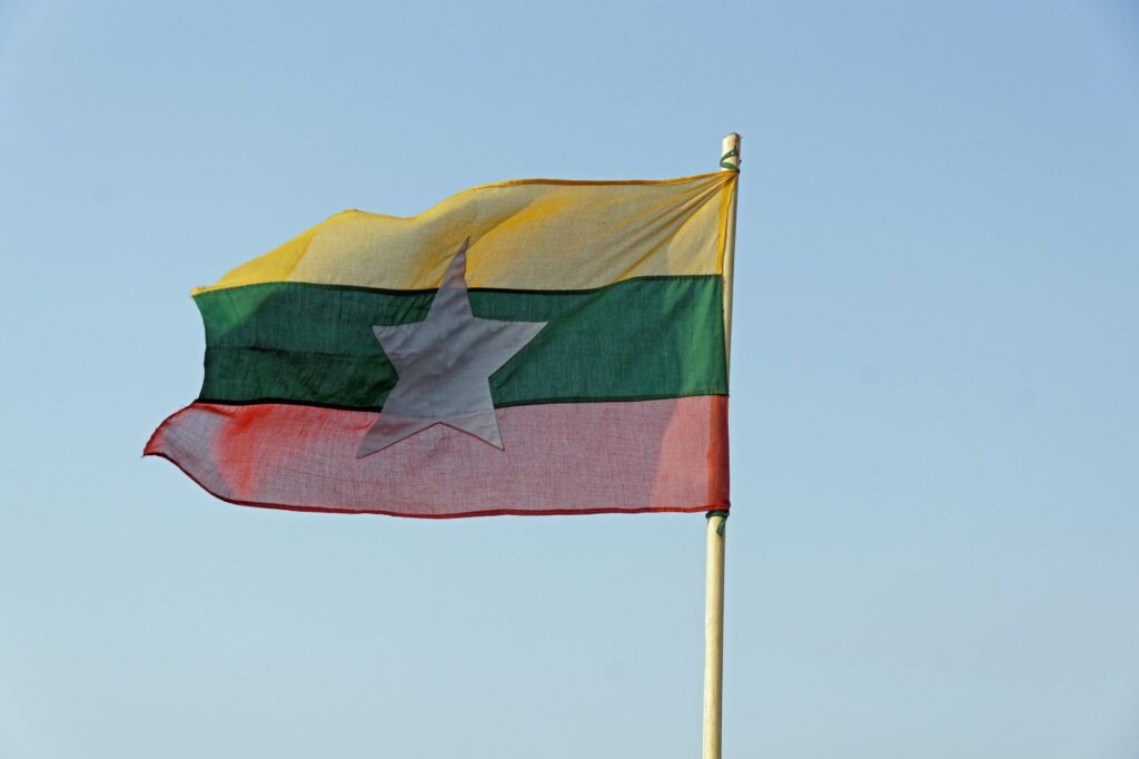 The national flag of Myanmar waving in a clear blue sky, symbolizing freedom and patriotism.