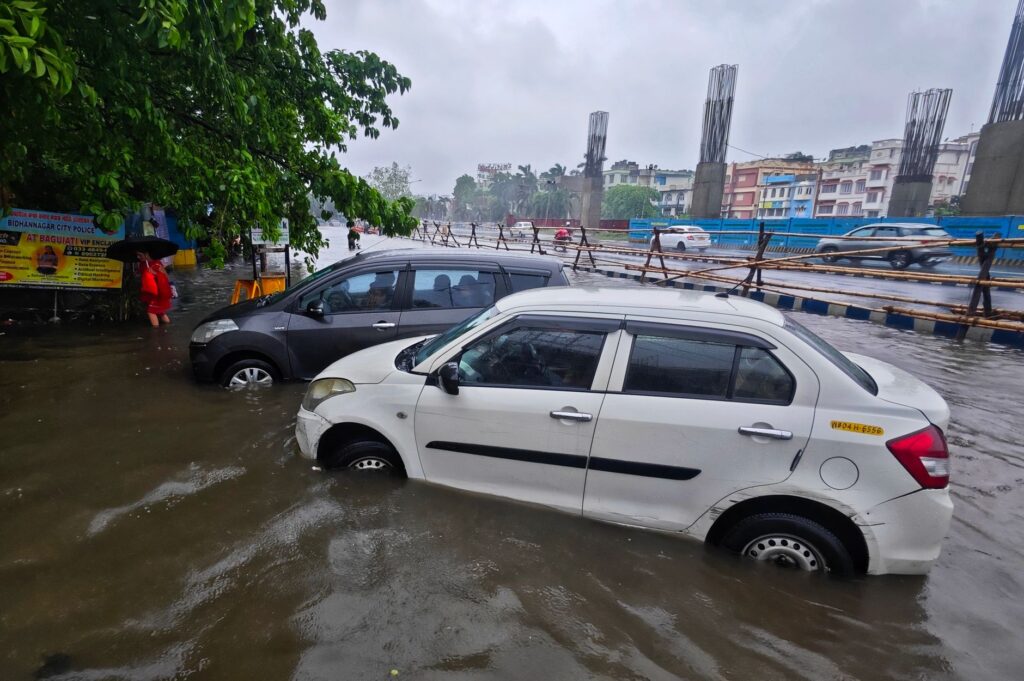 Vehicles submerged in a flooded street in Kolkata, India during a heavy monsoon rainfall.