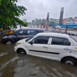 Vehicles submerged in a flooded street in Kolkata, India during a heavy monsoon rainfall.