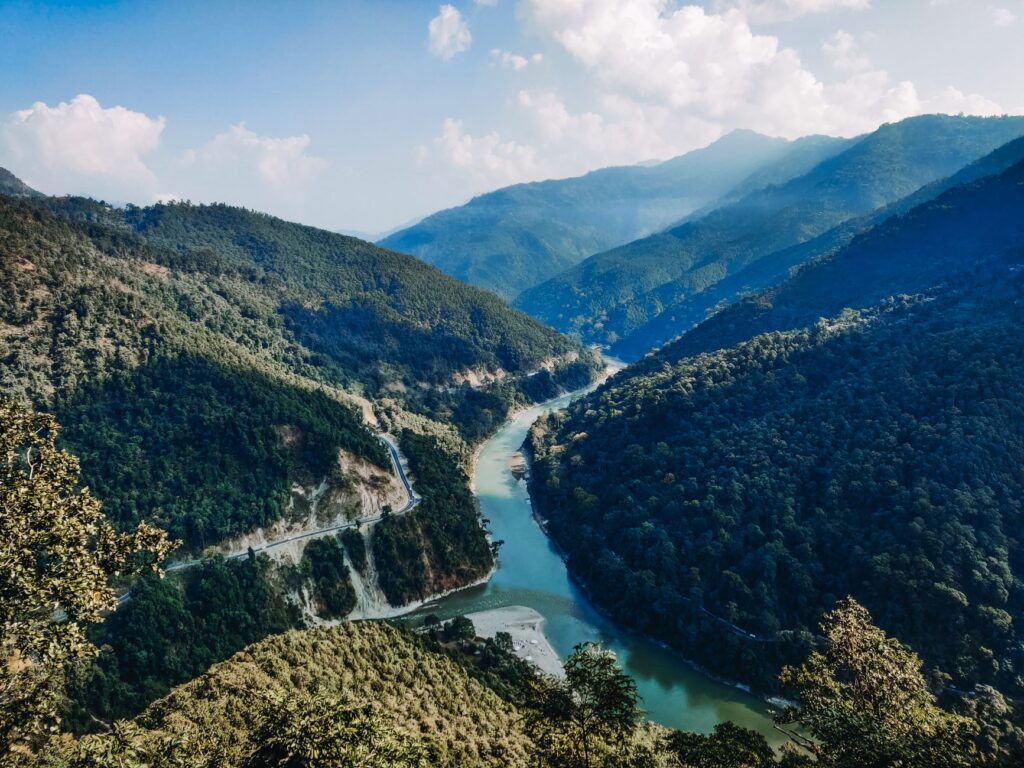 A breathtaking view of a river winding through the lush green valleys of Kalimpong in the Himalayas.