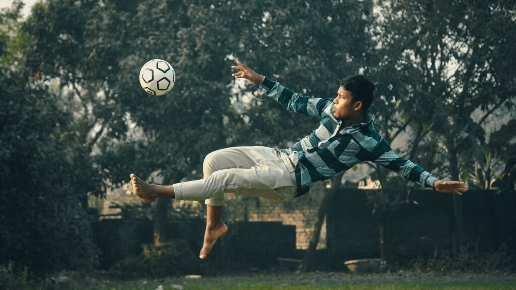 A young man performs a bicycle kick with precision while playing soccer outdoors in Kolkata.