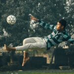 A young man performs a bicycle kick with precision while playing soccer outdoors in Kolkata.