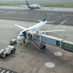 South African Airways plane docked at a gate in an airport, captured from an aerial view.
