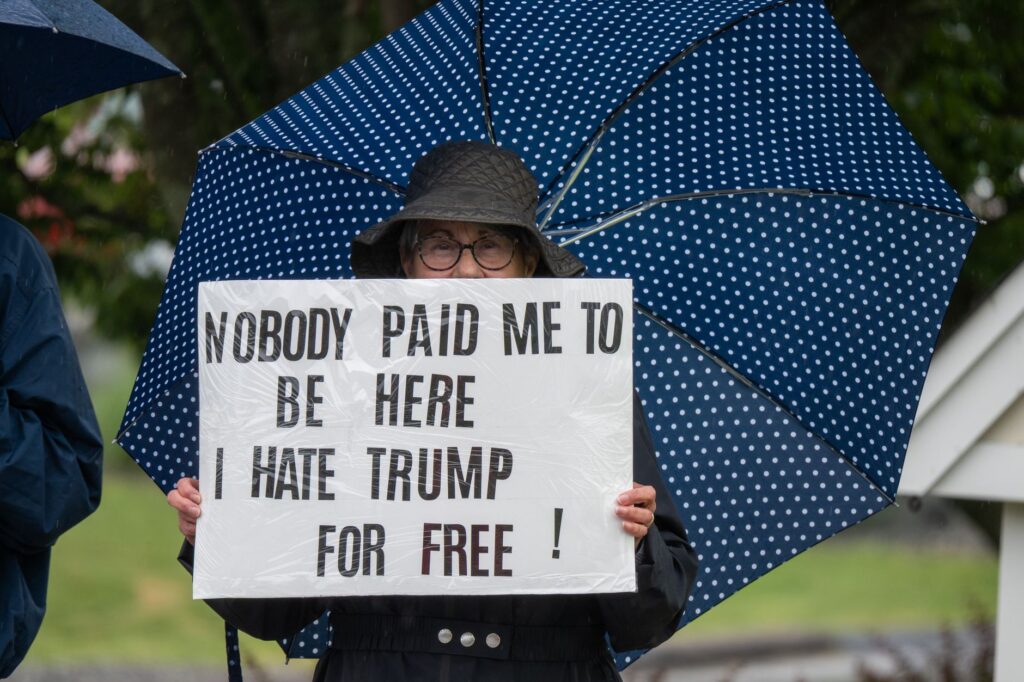 Protester with sign and umbrella during a rally in Rhode Island.