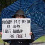 Protester with sign and umbrella during a rally in Rhode Island.