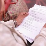 Man reviewing paperwork in Hindi during a seminar, showcasing focus and literacy.
